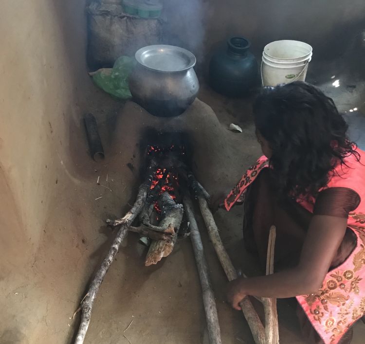 A young girl cooking with firewood on an improved cookstove in Odisha, India