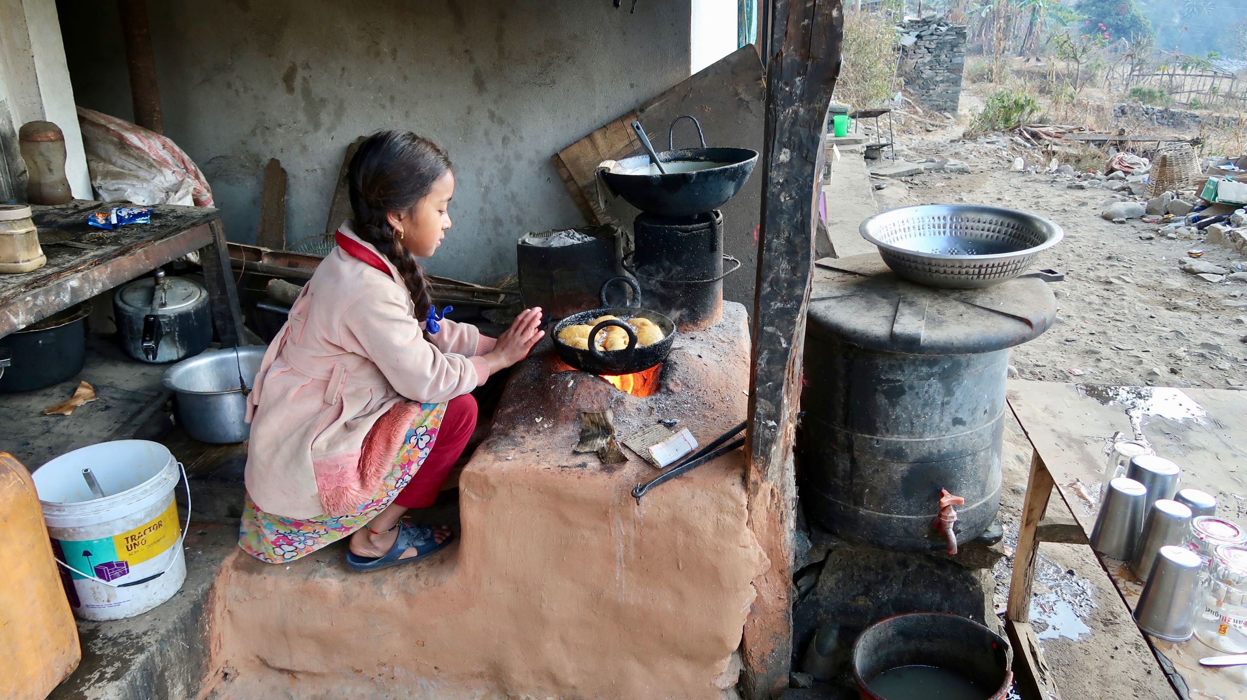 A girl cooking on an indoor stove in the Sindhupalchok District of Nepal.