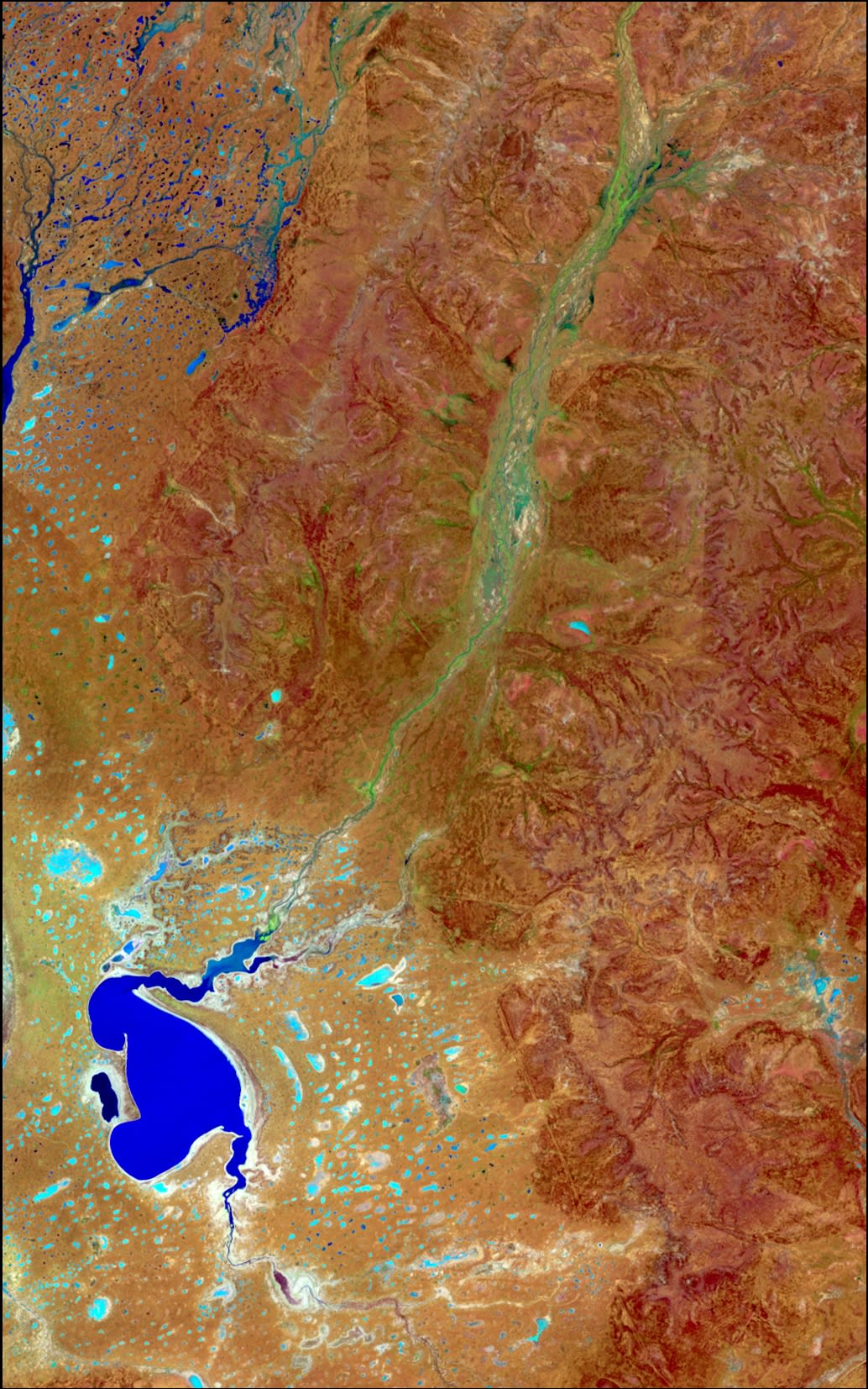This false colour Landsat image shows the rugged terrain of Currawinya National Park, in South West Queensland. The bright blue waters of Lake Numalla contrast with the orange sand flats near the lake and the dark orange hills to the north east. Boorara Creek cuts through these hills, and is visible as the green channel flowing into Lake Numalla. When this image was captured on 6 January 2015, the region had just received rainfall, which filled the usually dry salt pans and creek channels. These appear in various shades of blue and aqua.