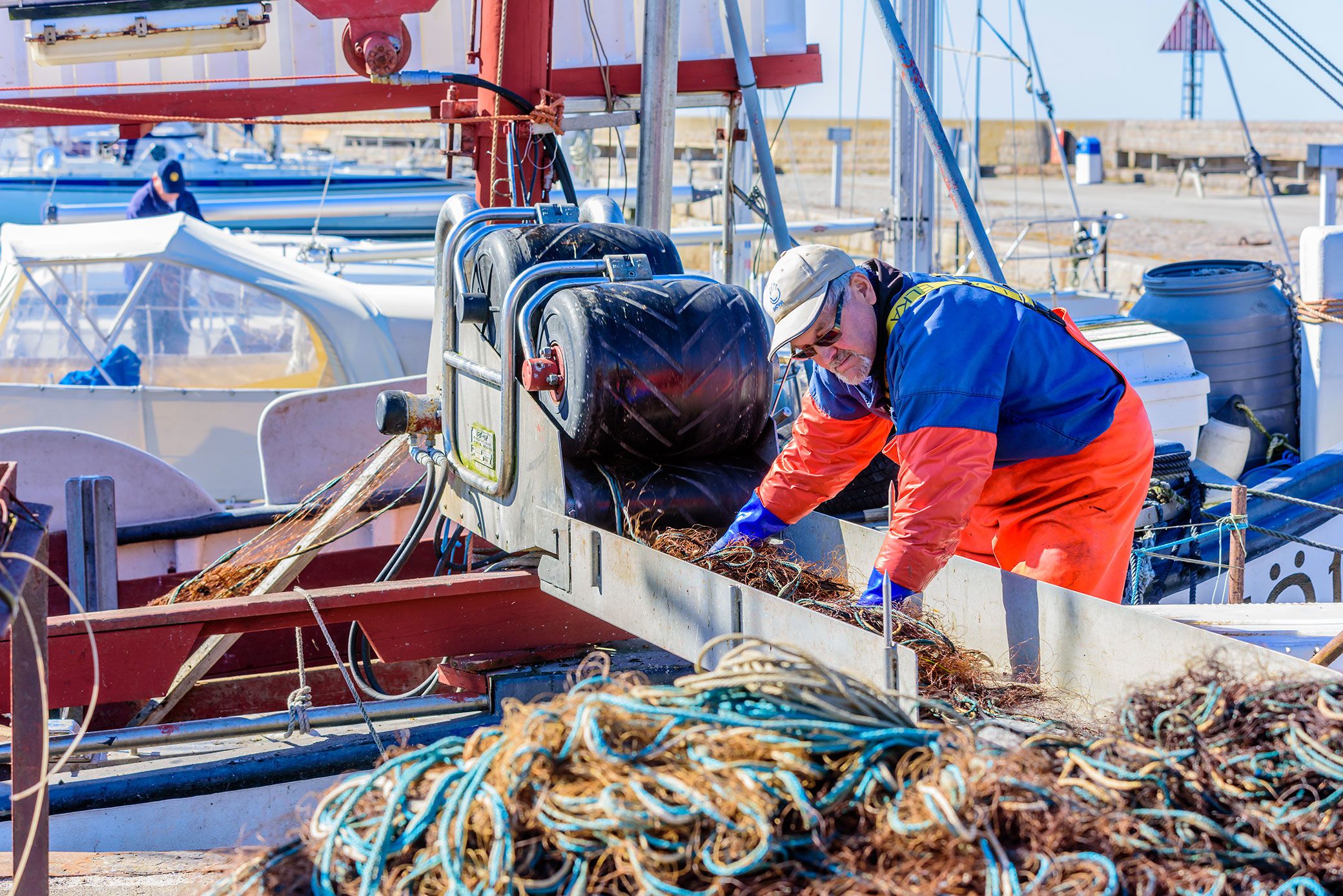 Fisherman standing ashore in the harbor, washing his fishing nets.