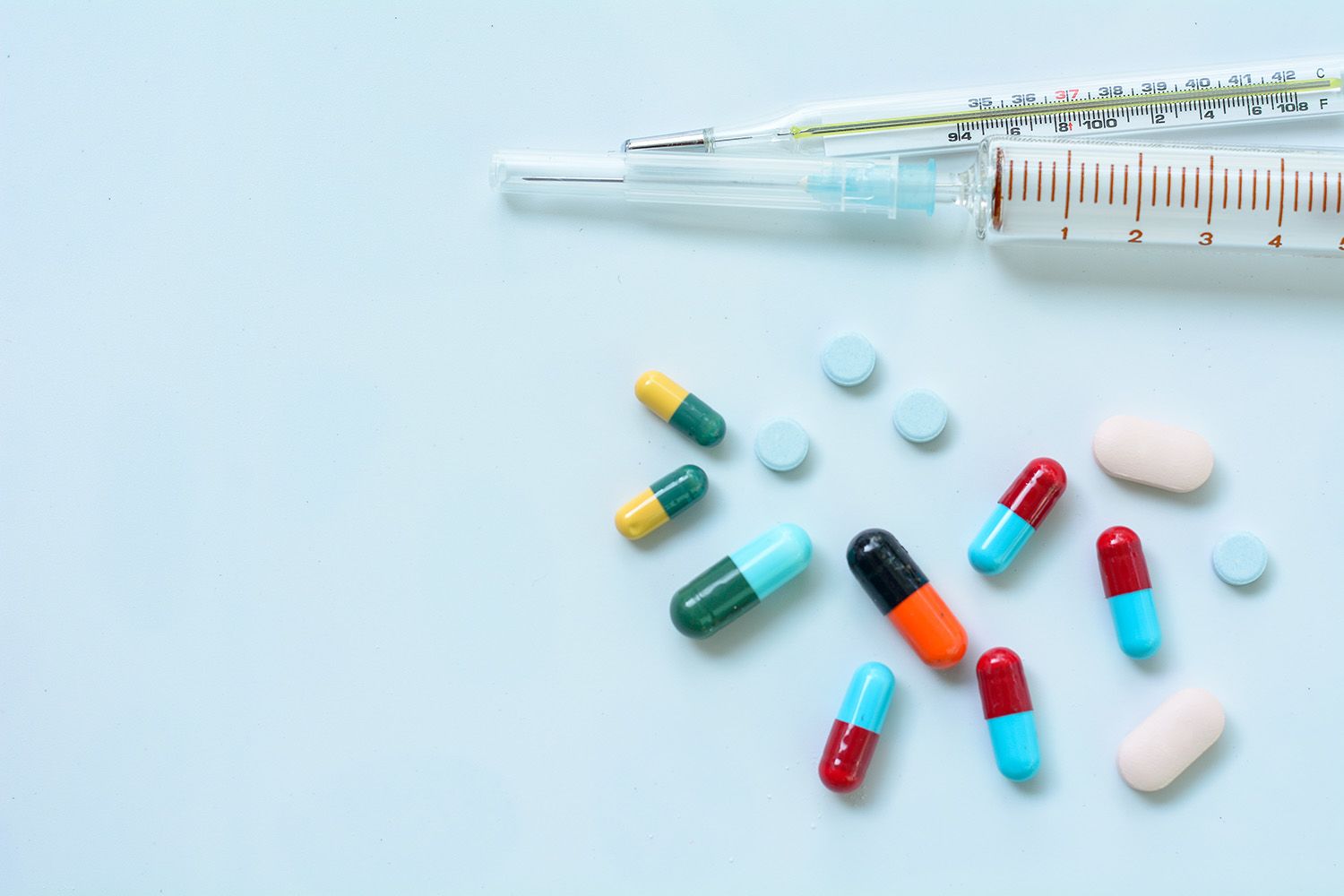 Pills and syringes on a desk.