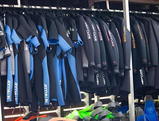 Wetsuits hanging on a rail