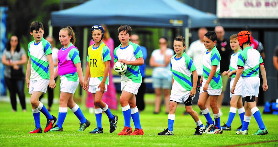 children walking midst game of junior rugby league