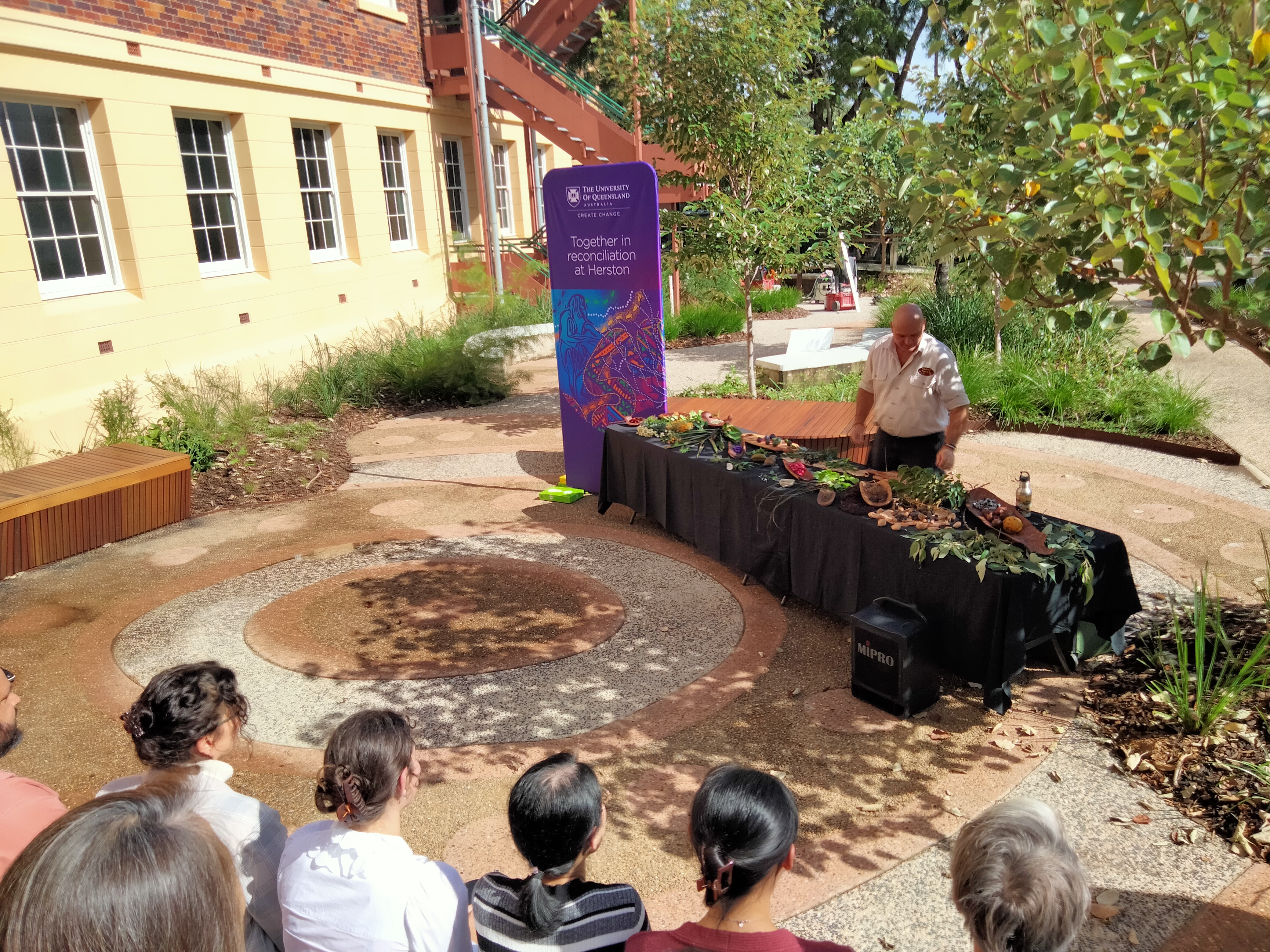 A group of people sitting and watching a presentation in the circular garden