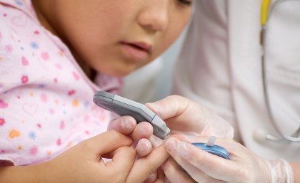 A child has a finger prick test for blood sugar levels