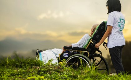 A carer with an elderly patient look at the sunset.
