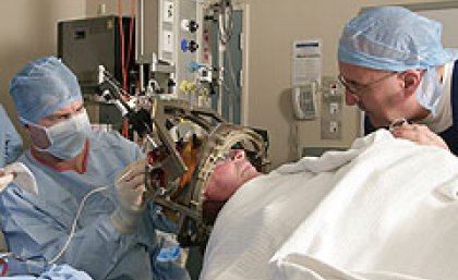 Professor of Clinical Neuroscience, Peter Silburn (right) talks with a patient about to undergo deep brain stimulation, as neurosurgeon, Dr Terry Coyne, implants the microelectrodes that will deliver the treatment.