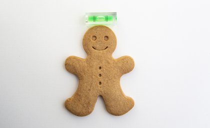 A gingerbread man underneath a spirit level.