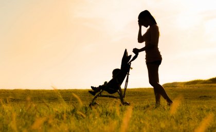 A silhouette of a mum with a baby in a pram.