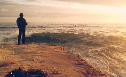 A fisherman fishes on the rocks