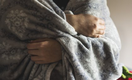 Man holding blanket around his upper body