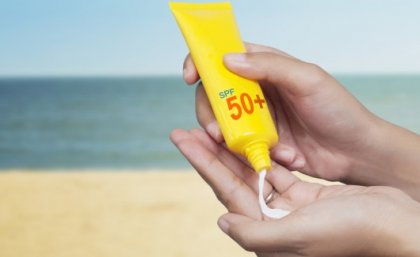 Pair of hands holding a tube of sunscreen, and squeezing some into one palm