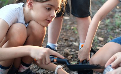 A young girl digs in the dirt to fill a Soils for Science sample bag.