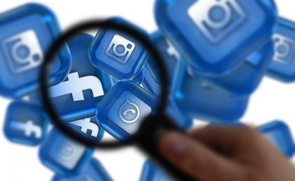 Magnifying glass over social media icons.