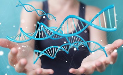 A woman stands in front of a blue background with graphic depiction of DNA