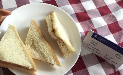 A plate of white, triangular sandwiches on a table with a red and white checkered table cloth 