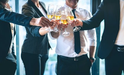 A group of people dressed in corporate wear clinking champagne glasses