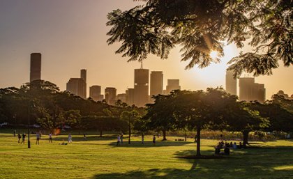 People in New Farm Park in the late afternoon sun with the Brisbane urban skyline in the background.