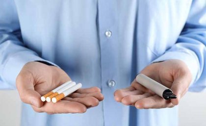 Person holding cigarettes in one hand and a vape in the other