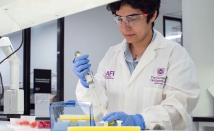A woman wearing a lab coat doing an experiment in a science lab.