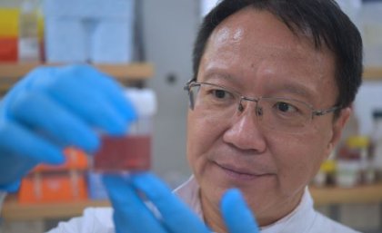 Researcher in a lab examining a container of sample nanoparticles used in breast cancer research. 