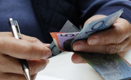 Close up of hands holding Australian dollar notes.