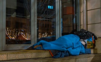 A homeless man asleep on the sidewalk