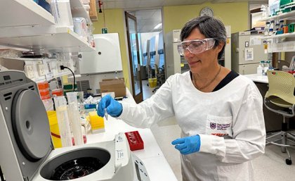 Professor Ranjeny Thomas wearing a lab coat and safety glasses working in the lab