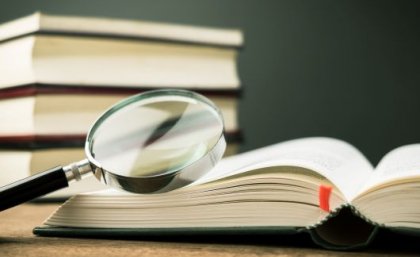Image: Adobe. A stack of novels with a magnifying glass.