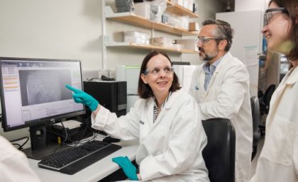 QEDDI Drug Discovery Team Leader Dr Kim Beaumont, Head of QEDDI Brian Dymock, and Medicinal Chemistry Team Leader Dr Rebecca Pouwer. Three scientists in white lab coats looking at a computer screen.