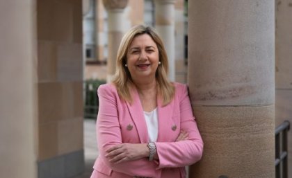Adjunct Professor Annastacia Palaszczuk. A woman in a pink blazer leans against a sandstone pillar, smiling at the camera.