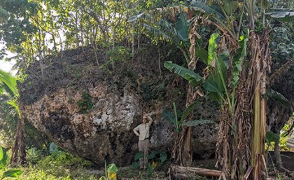 Martin Köhler stands in front of the Maka Lahi boulder. a man stands in front of a large rock holding a measuring tape