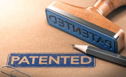 Image: Adobe. A close up of a blue stamp with the word 'patented' stamped on a brown folder.