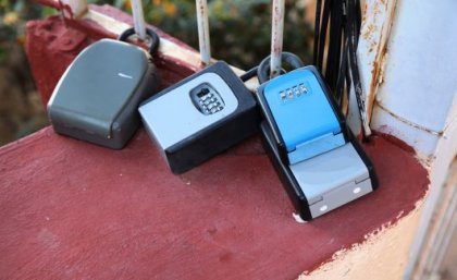 Image: Adobe. Three key boxes attached to a gate at a holiday rental complex