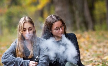 Two young women using vapes outdoors. Image, Adobe.