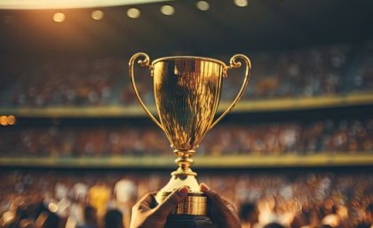 Image: Adobe. A gold trophy being help un in a stadium.