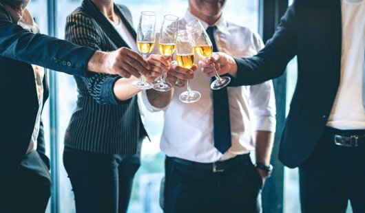 A group of people dressed in corporate wear clinking champagne glasses