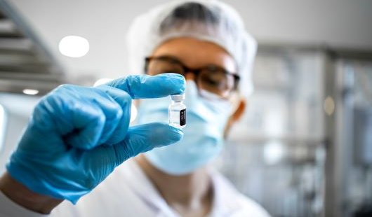A man in a laboratory holds a vial up to his face