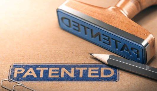 A close up of a blue stamp with the word 'patented' stamped on a brown folder. 