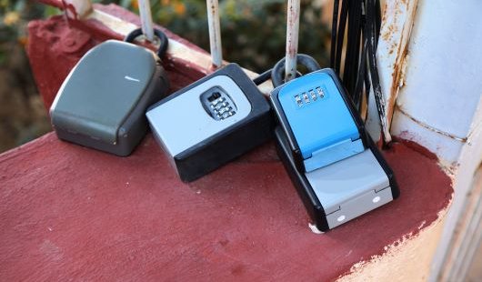 Three key boxes attached to a gate at a holiday rental complex