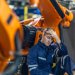 Image: Adobe A tired worker sits in front of machinery with his hand on his head
