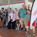 Crossroad Arts is an inclusive arts organisation for people with a disability or who are deaf. Image: Crossroad Arts. A group of people smiling at the camera holding a flag that says "Cross Roads".