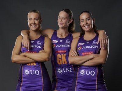 3 Firebirds players dressed in their purple netball uniforms smiling.
