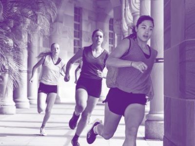 Three female athletes running around sandstone building with purple overlay.