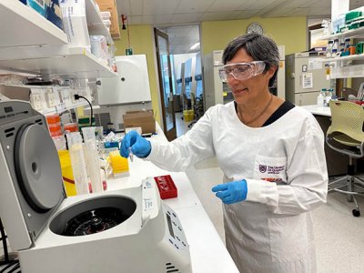Professor Ranjeny Thomas wearing a lab coat and safety glasses working in the lab