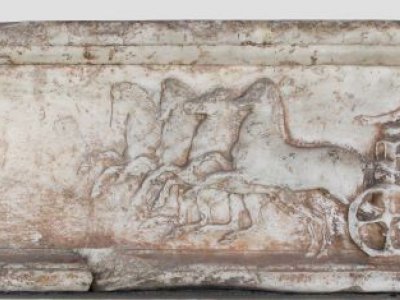 A stone carving featuring a chariot being pulled by four horses.