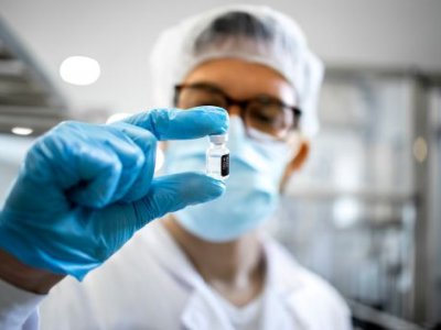 A man in a laboratory holds a vial up to his face