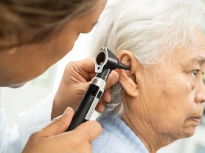 A audiologist inserting a stethoscope into a elderly patient's ear