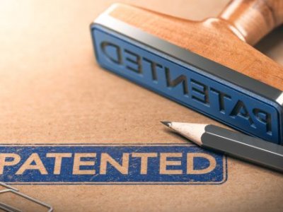 A close up of a blue stamp with the word 'patented' stamped on a brown folder. 