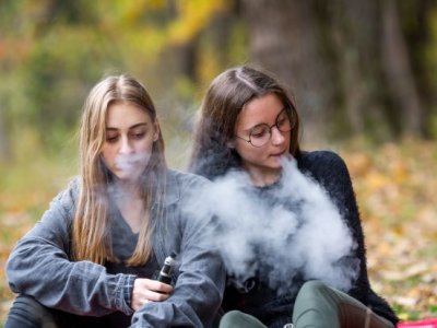 Two young women using vapes outdoors. Image, Adobe.